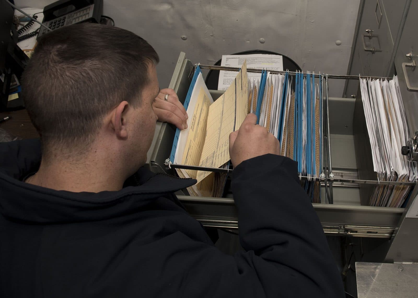 Back office specialist filing invoice documents into an organized folder system